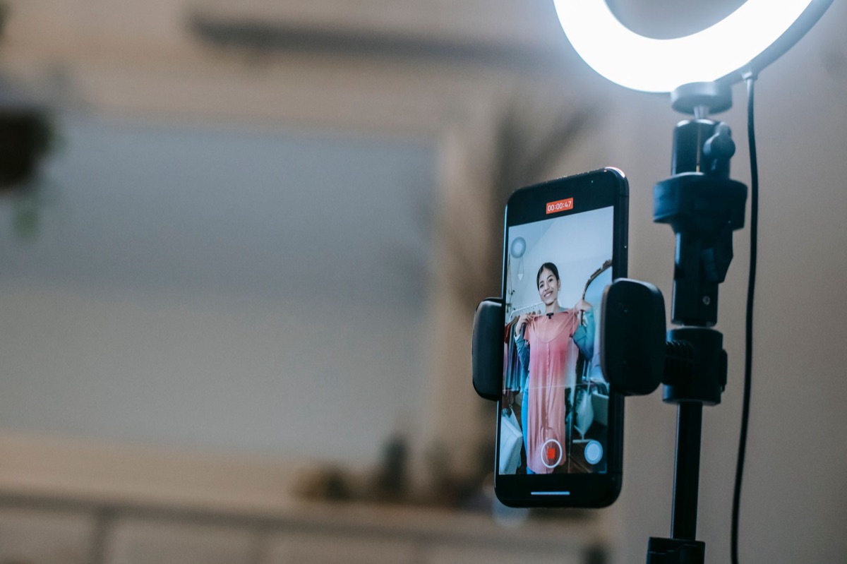 Smartphone tripod setup on a wooden surface with a reflective surface in the background