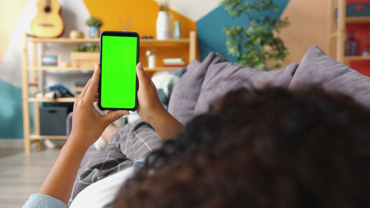 Persona filming with smartphone in modern room