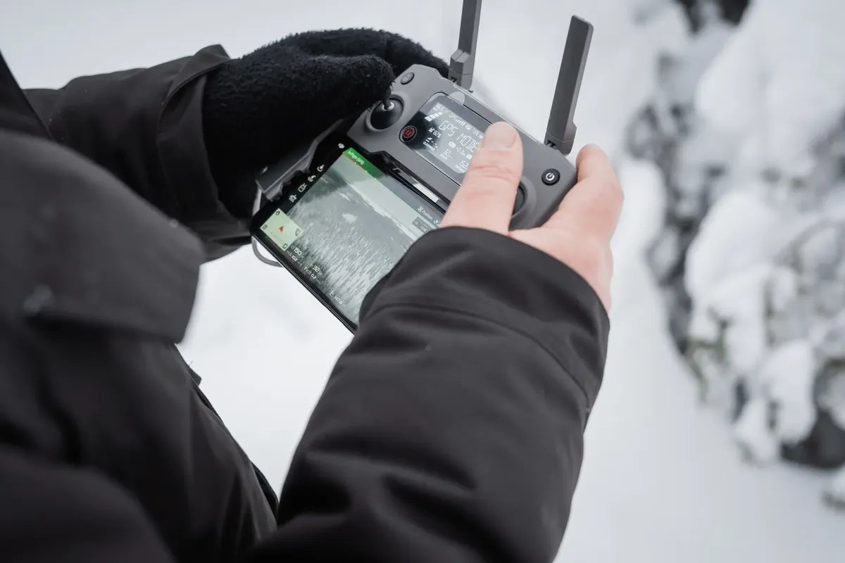 Close-up of hands operating a drone controller in snowy Finland. Winter technology adventure.